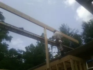 Carpenter setting a ridge beam over a new addition frame — Ice Dam Removal by Roofing Brothers in Commerce