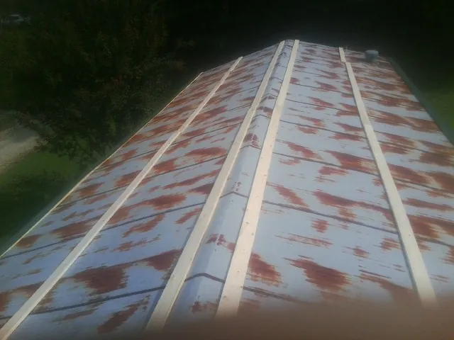 Rusted metal roof panels with new wood purlins before replacement — Storm Damage Roof Repair in Commerce by Roofing Brothers