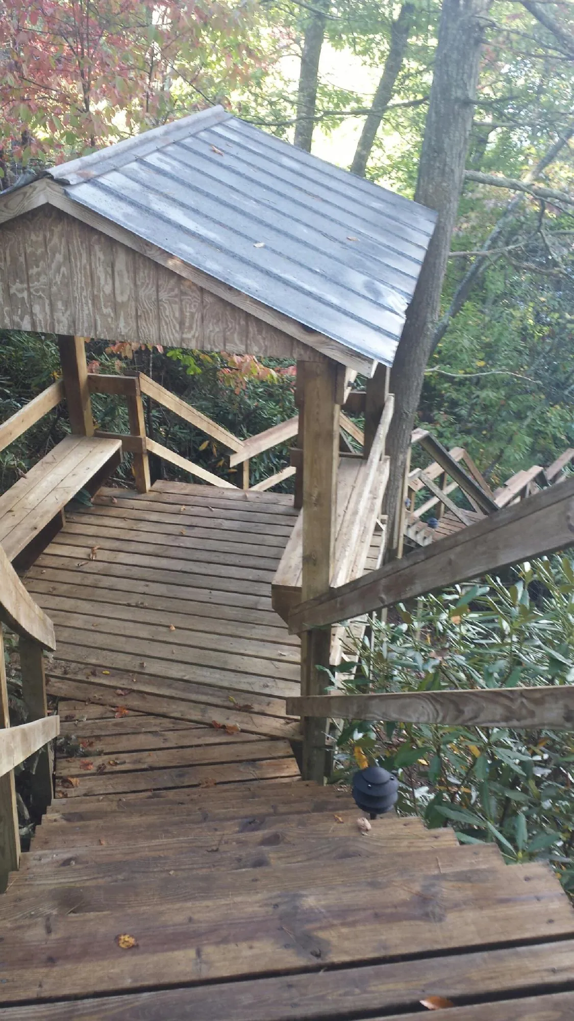Metal roofed shelter over wooden steps on a wooded walkway — Skylight Repair & Installation work by our crew in Commerce